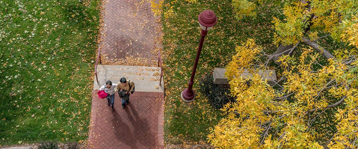 drone view of two people walking on campus